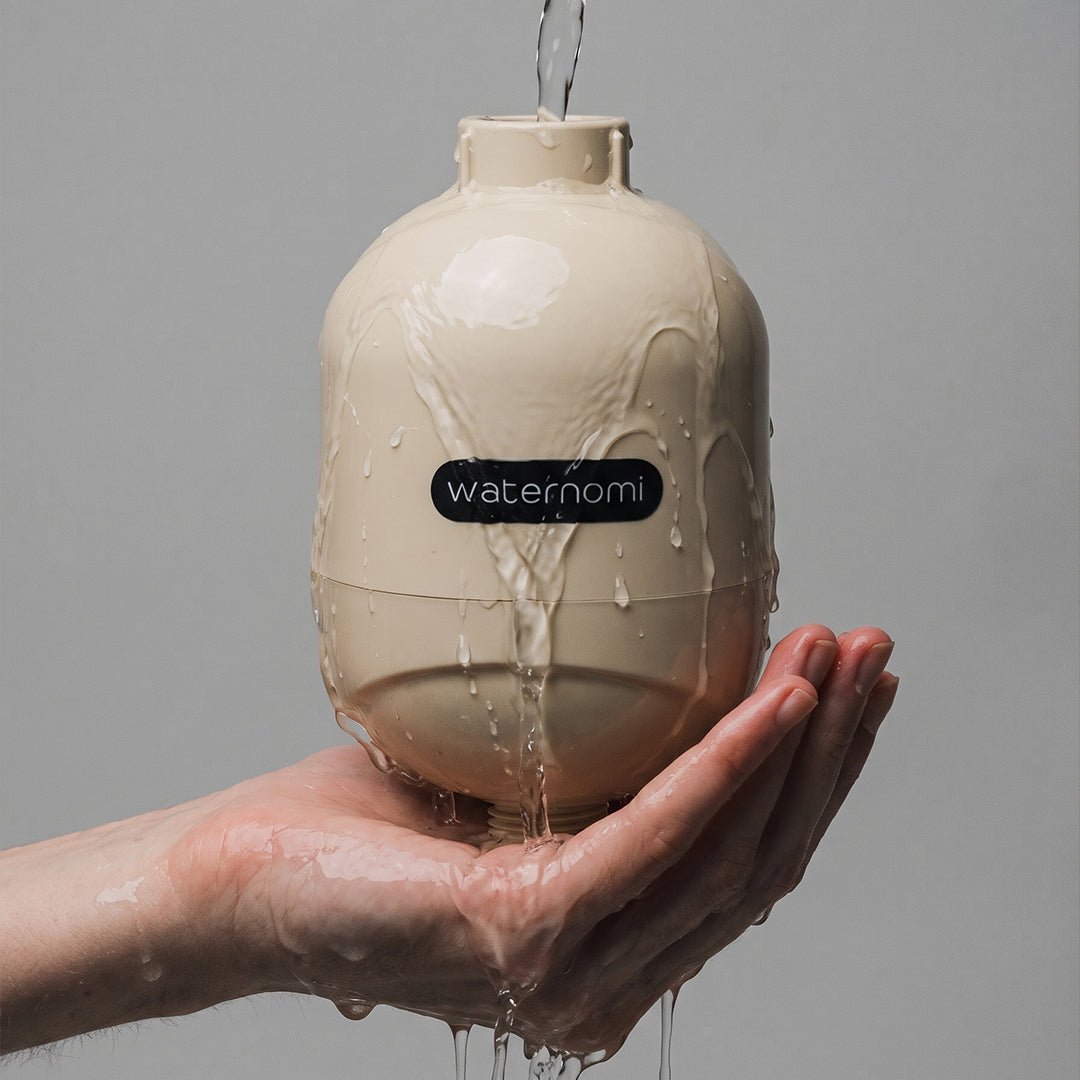 Water flowing over the Waternomi shower filter in a hand